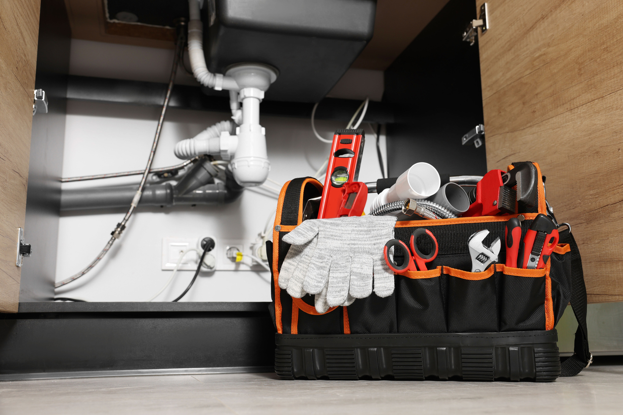 Plumber's tool bag on floor under kitchen sink